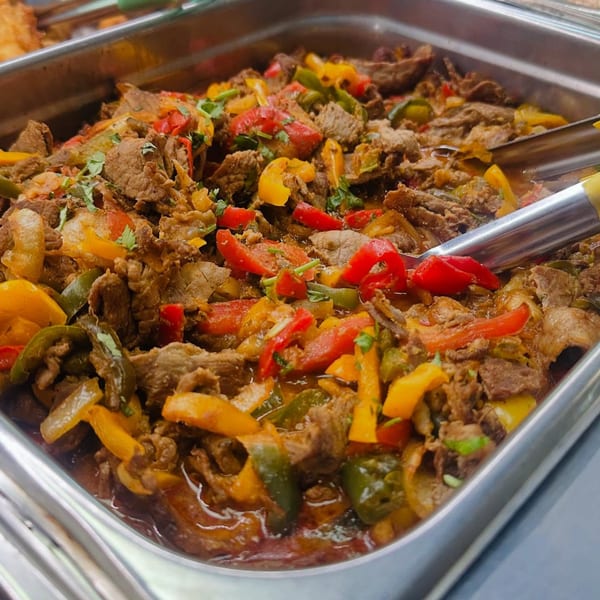 Close-up of AzucaR's Latin-American beef fajitas with colorful bell peppers and cilantro in a serving tray.